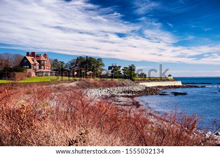 The rocky coast and cliffwalk of Newport Rhode Island in the united states under blue sky and white clouds. Royalty-Free Stock Photo #1555032134