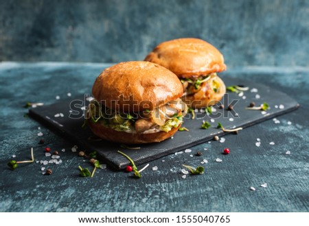 Fresh tasty burgers with roasted chicken, potato, micro greens and different herbs on the rustic background. Selective focus. Shallow depth of field.
