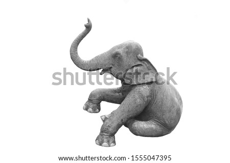 The statue of an elephant in a sitting position. It is in black and white color.
