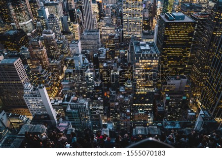 Aerial view of glowing high rise buildings of Manhattan district with lighted windows located in New York city on background of evening sky. Developed infrastructure midtown with skyscrapers