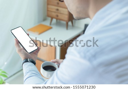 Mockup image blank white screen cell phone.men hand holding texting using mobile on desk at home office. background empty space for advertise text.people contact marketing business and technology