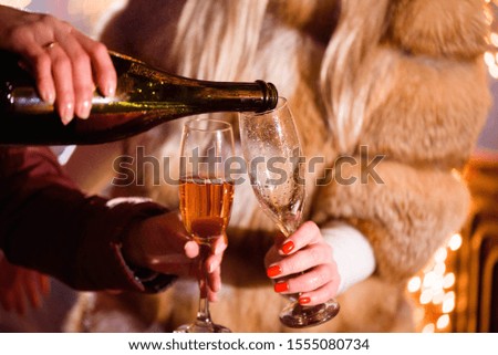 Pouring champagne into glass at party, close up, winter.