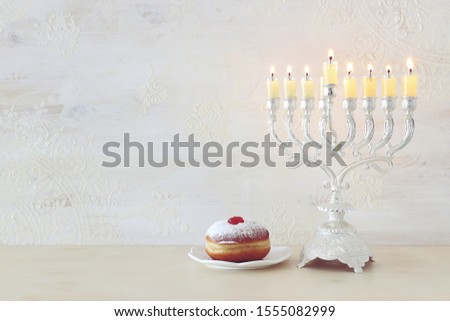 religion image of jewish holiday Hanukkah  with spinning top and doughnut over white background