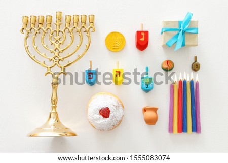 religion image of jewish holiday Hanukkah with menorah (traditional candelabra), spinning top and doughnut over wooden white background. top view, flat lay
