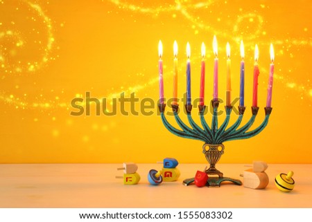 religion image of jewish holiday Hanukkah  with menorah (traditional candelabra)and spinning top over yellow background