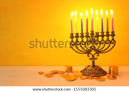 religion image of jewish holiday Hanukkah with menorah (traditional candelabra)and spinning top over yellow background