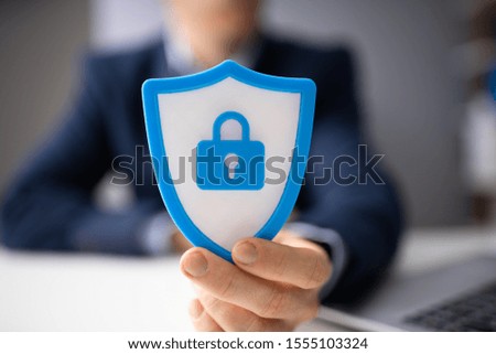 Close-up Of A Businessperson's Hand Holding Blue Shield Security Icon