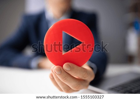 Close-up Of A Man's Hand Holding Red Play Icon
