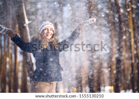 Happy young woman plays with a snow in sunny winter day. Girl enjoys winter, frosty day.  Playing with snow on winter holidays, a woman throws white, loose snow into the air. Walk in winter forest.