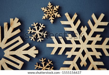Flat lay background.Handmade wooden snowflakes for winter holidays.Christmas Eve & Happy New Year decorations made from rustic wood material on blue paper background shot from above in flat layout