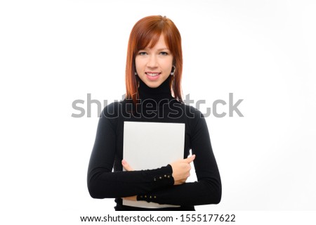 Portrait of a pretty red-haired student girl with long straight hair on a white background in a black sweater with a folder in her hands. Talking, showing emotions, smiling.