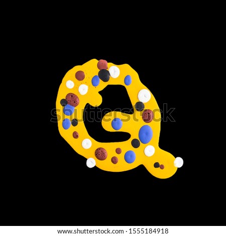 latin alphabet . letter Q  . yellow water paint on a black background. colored drops.