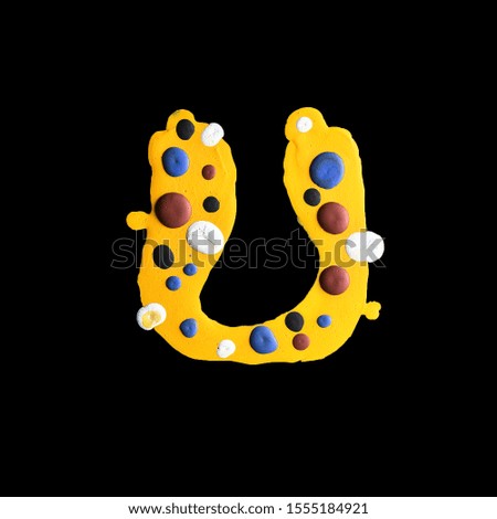 latin alphabet . letter U . yellow water paint on a black background. colored drops.