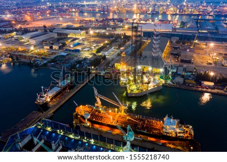 Aerial view of a jack up oil drilling rig and dry dock ship in the shipyard for maintenance during suset time