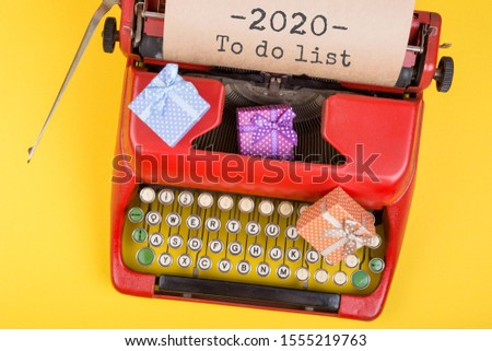Christmas concept - red typewriter with the text "2020 To do list" and gift boxes on yellow background