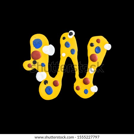 latin alphabet. letter W . yellow water paint on a black background.
