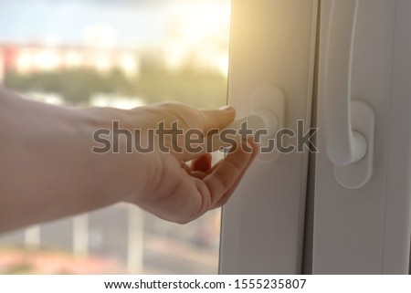 male hand holds handle of modern glass window or door and open frame for ventilation of house living room or bedroom, sun light outside