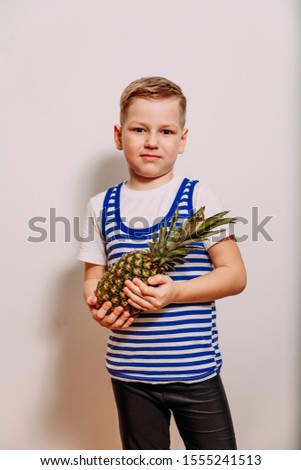 Boy holds pineapple in his hands on white background
