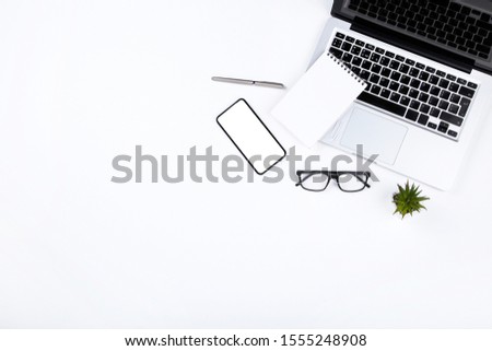 Laptop computer with smartphone, glasses and notepad on white background