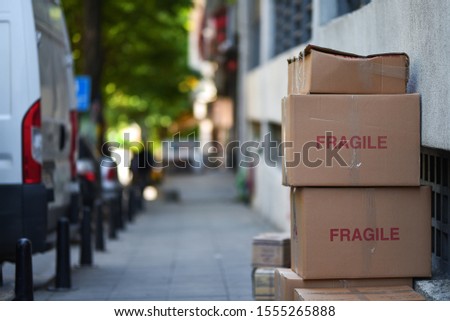 stacked cardboard boxes of delivery service with sign fragile on background van