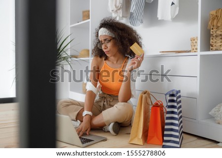 Displeased young woman holding gold card and using laptop stock photo