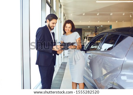 A young woman buys a new car in an auto salon