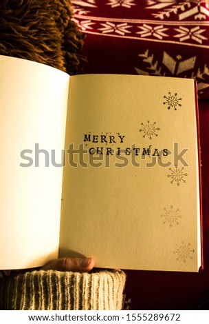 Retro style merry christmas text on the book. Vintage picture with hand holding old paper. Red and brown nice background