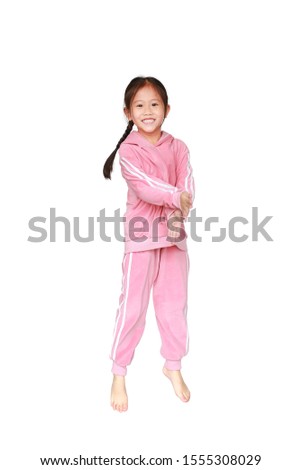 Portrait of smiling little Asian kid girl in pink tracksuit or sport cloth doing exercises isolated on white background.