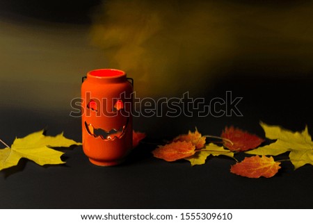 Squash pumpkin orange ceramic candle with burning flame, flying spooky ghosts and autumn leaves on black background.