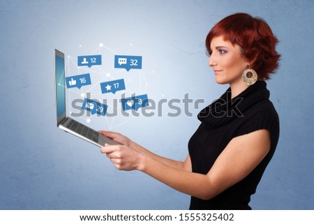 Woman holding laptop with different types of social media symbols and icons