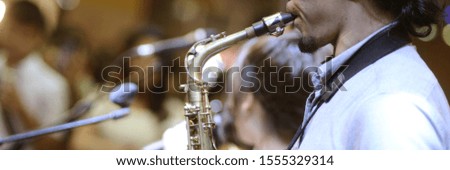 The musician is blowing his saxophone