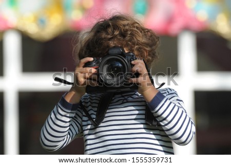 Child learns to take pictures in a park with a professional reflex camera