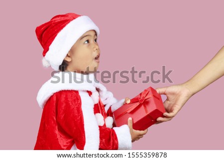 Portrait of Asian cute girl wearing santa costumes giving red gift box with copy space isolated on pink background. christmas concept.