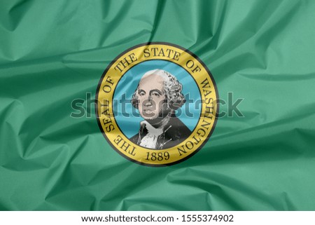 Fabric flag of Washington. Crease of Washington flag background, the states of America. The state seal, displaying an image of state namesake George Washington on green.