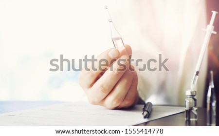 A man signs a medical document. Medical equipment on the table. Stethoscope and ampoules with syringes. Makes notes in office. Medical center.