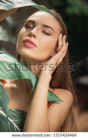 Close up of nice lady standing near green leaf stock photo