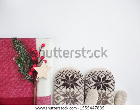 white mittens with ornament  red scarf twig spruce bunch of berries star made of wood on a white background