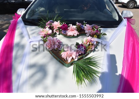 bouquet of beautiful pink and purple flowers in the shape of a heart symbol on a white wedding car, flora, decoration, design, two ribbons Royalty-Free Stock Photo #1555503992