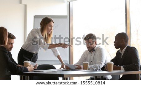 Angry millennial businesswoman lead meeting scold disorganized unprofessional young african American employee, furious young woman ceo lecture talk to irresponsible careless biracial male worker Royalty-Free Stock Photo #1555510814