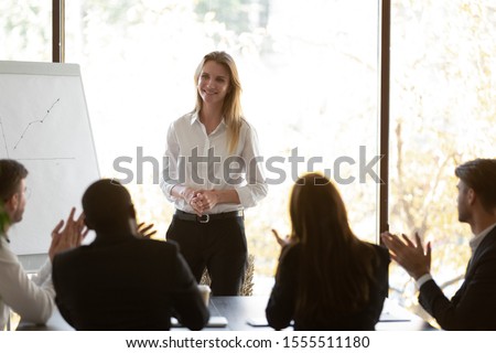 Multiethnic employees clap hands applaud greeting smiling successful female coach presenter at meeting, multiracial diverse worker give warm welcome to confident woman speaker, acknowledgment concept Royalty-Free Stock Photo #1555511180