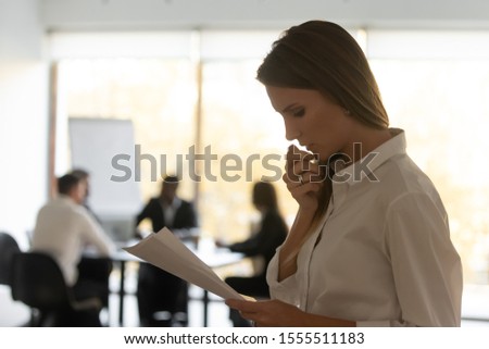 Anxious millennial Caucasian woman stand outside boardroom read look through papers get ready for speech, scared frustrated female speaker repeat consider document worried before public speaking Royalty-Free Stock Photo #1555511183