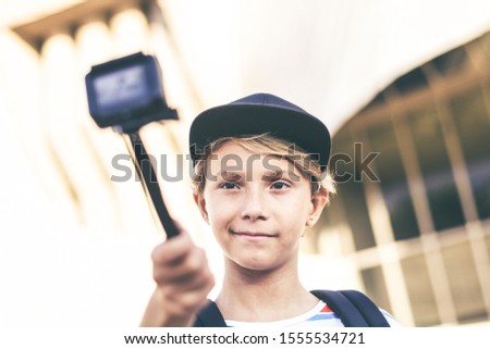 Closeup view of a teen with hat taking selfie with action cam Young blogger making video for social story with camera. Student having fun with new multimedia technology device. Trends tech concept.