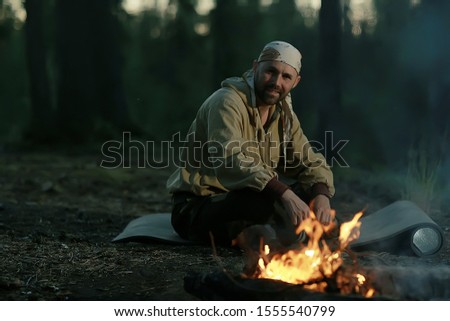 tourist bonfire huntsman, a man in the taiga basking in the fire