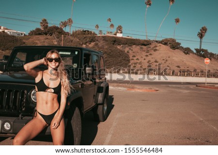 surfer girl standing by a car on parking spot. california