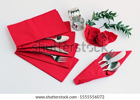 Special folded,luxury red paper napkins with cutlery set and napkin rings on the white surface.Christmas or New Year Concept.