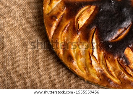 piece of cake. failed apple pie. burnt on top and the dough did not rise during baking. textured burnt pie crust. lies on linen Royalty-Free Stock Photo #1555559456