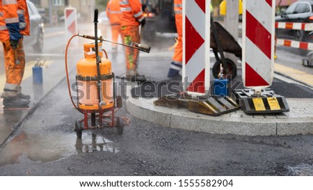 Construction workers repairing the street on a rainy day.