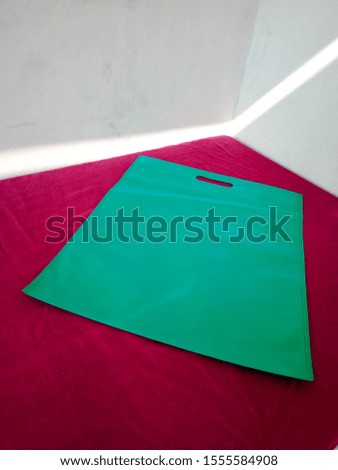Green D cut Eco Friendly Bag, Non Woven Polypropylene Bag on red table, Reusable shopping bag