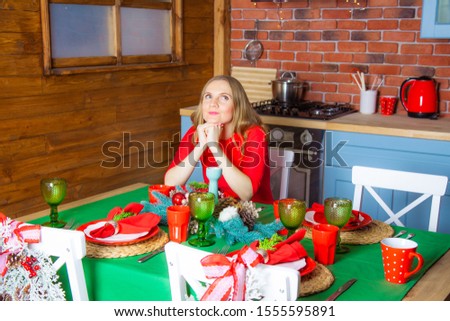 A beautiful lonely young woman alone on Christmas evening is sad at the festive table, because no one came to visit her, New Year, winter season