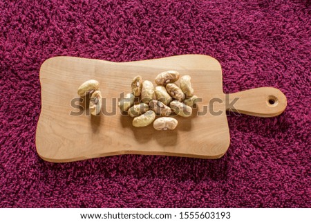 White beans on a wooden board, seeds of annual garden bean plant with long narrow fruits 